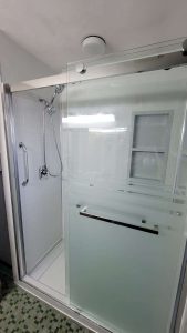 A NEWPRO Elite Collection shower with white walls and chrome fixtures 